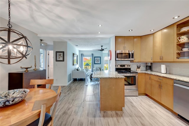 kitchen with light brown cabinetry, light stone counters, tasteful backsplash, a center island, and stainless steel appliances