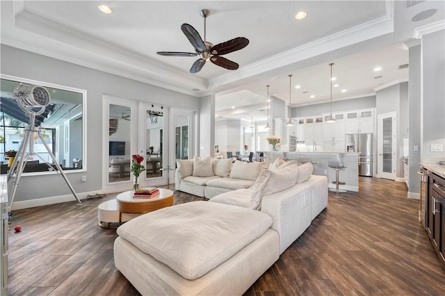 living room featuring ceiling fan, dark hardwood / wood-style floors, ornamental molding, and a tray ceiling