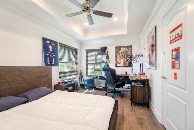 bedroom featuring ornamental molding, a tray ceiling, ceiling fan, and hardwood / wood-style flooring