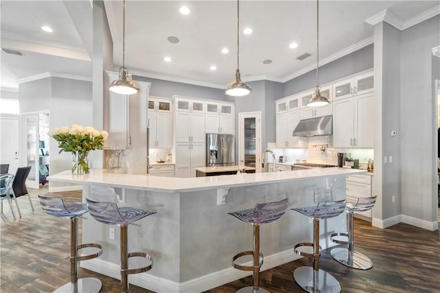 kitchen with a kitchen breakfast bar, stainless steel fridge with ice dispenser, white cabinetry, and hanging light fixtures