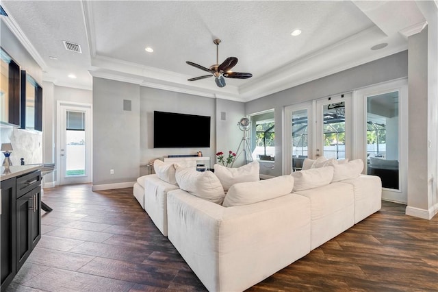 living room with ceiling fan, dark hardwood / wood-style floors, a textured ceiling, and a tray ceiling