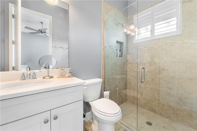 bathroom with ceiling fan, vanity, a shower with shower door, and toilet