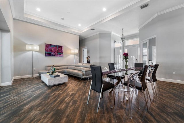 dining room with ornamental molding, a tray ceiling, and dark wood-type flooring