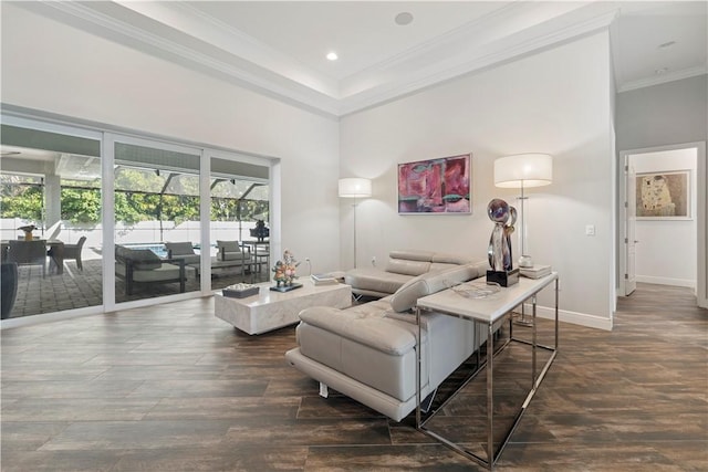 living room with plenty of natural light, ornamental molding, dark wood-type flooring, and a towering ceiling