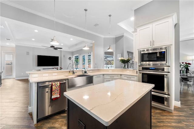 kitchen featuring stainless steel appliances, sink, pendant lighting, white cabinets, and a center island