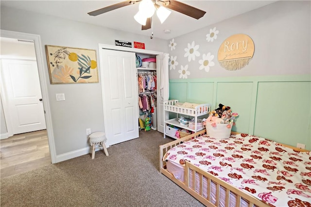 bedroom with a wainscoted wall, a decorative wall, a ceiling fan, and carpet floors