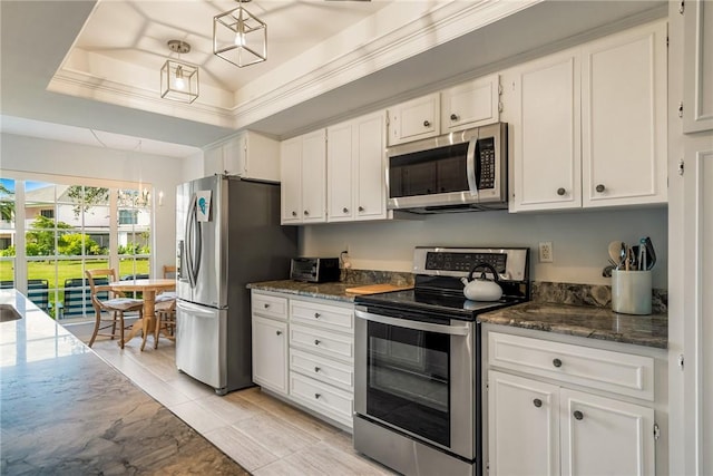 kitchen featuring white cabinetry, stainless steel appliances, a tray ceiling, decorative light fixtures, and dark stone counters