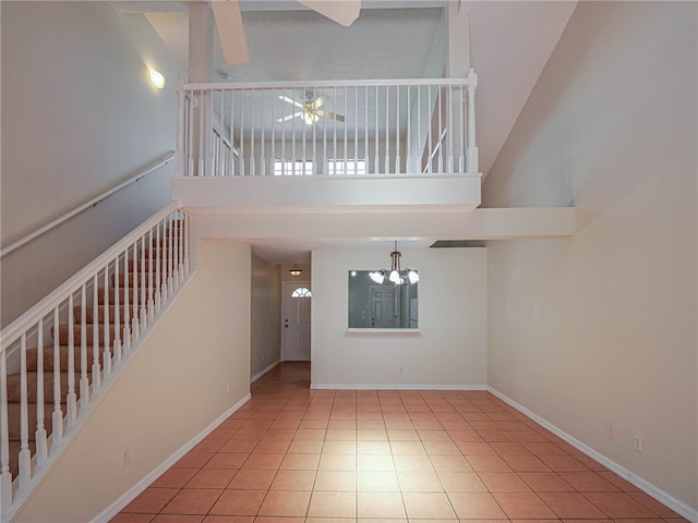 interior space with a towering ceiling, ceiling fan with notable chandelier, and tile patterned floors