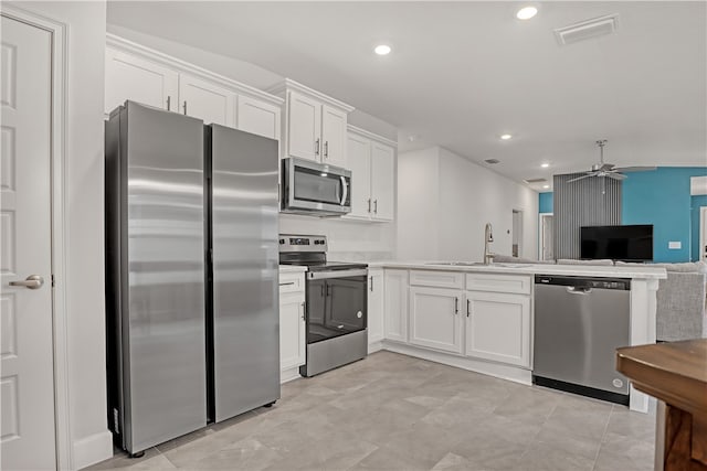 kitchen with stainless steel appliances, vaulted ceiling, ceiling fan, sink, and white cabinetry