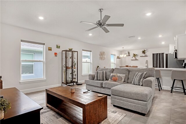 tiled living room featuring ceiling fan with notable chandelier