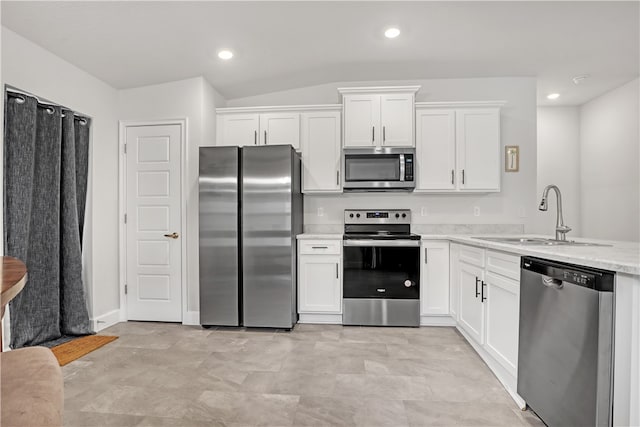 kitchen with sink, white cabinets, stainless steel appliances, and vaulted ceiling