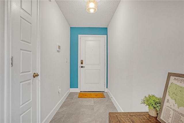 entryway with light tile patterned floors and a textured ceiling