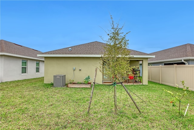 back of property featuring a lawn and central air condition unit