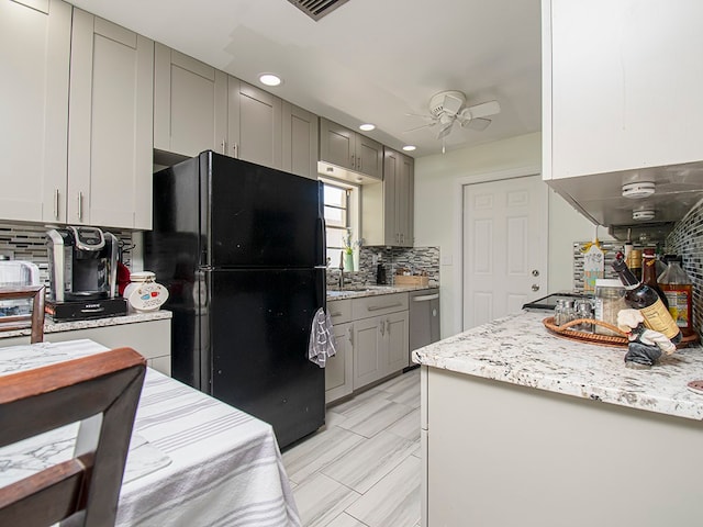 kitchen with ceiling fan, stainless steel dishwasher, black refrigerator, gray cabinetry, and decorative backsplash