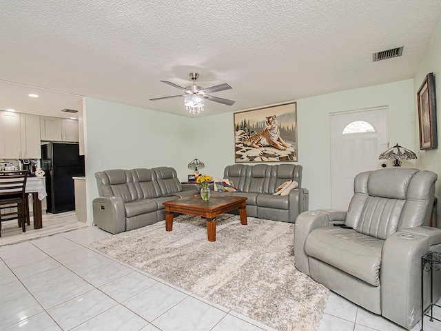 living room with a textured ceiling, ceiling fan, and light tile patterned floors