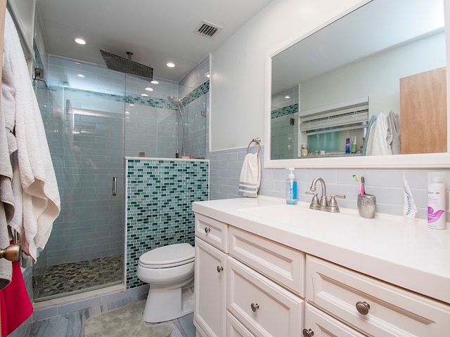 bathroom with walk in shower, vanity, tile walls, and toilet