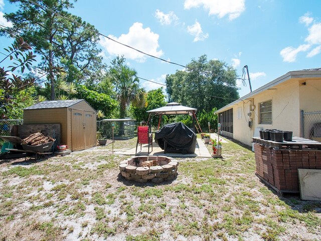 view of yard featuring a gazebo, an outdoor fire pit, a storage shed, and a patio area