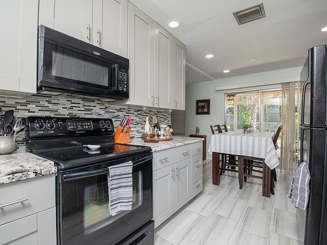 kitchen with light stone countertops, white cabinetry, black appliances, and decorative backsplash