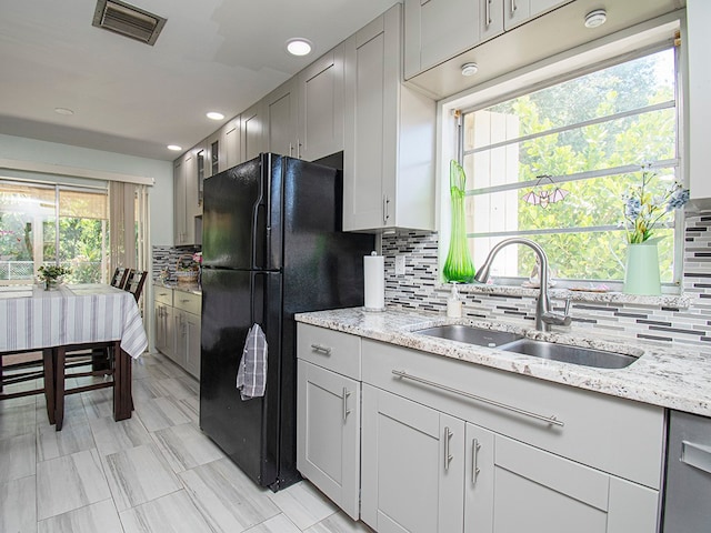 kitchen featuring black refrigerator, tasteful backsplash, sink, and plenty of natural light