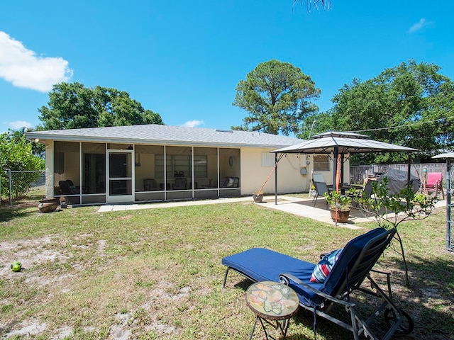 rear view of property with a gazebo, a lawn, a sunroom, and a patio area