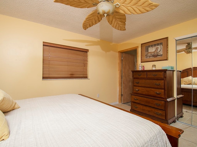 tiled bedroom with a textured ceiling, ceiling fan, and a closet