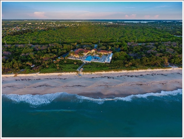 aerial view at dusk with a water view and a view of the beach