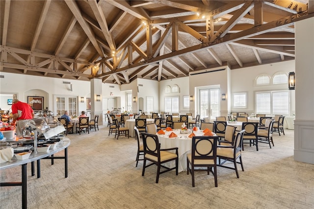 carpeted dining room with beam ceiling and high vaulted ceiling