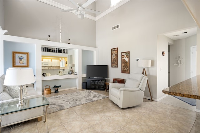 living room featuring crown molding, ceiling fan, and a high ceiling