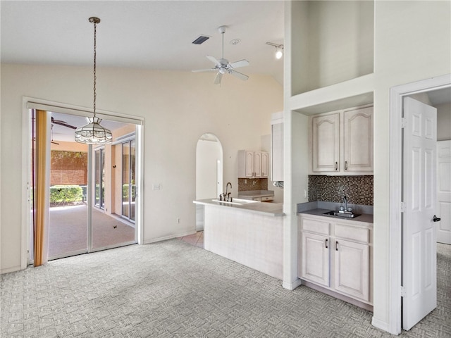 kitchen featuring hanging light fixtures, light colored carpet, sink, and tasteful backsplash