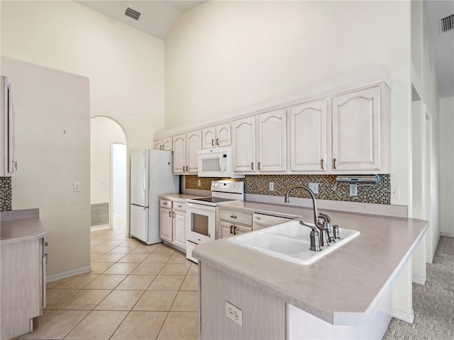 kitchen featuring high vaulted ceiling, kitchen peninsula, sink, and white appliances