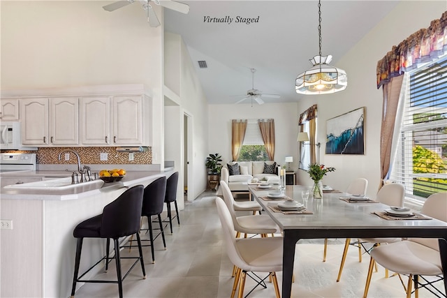 dining space featuring high vaulted ceiling, ceiling fan, and sink