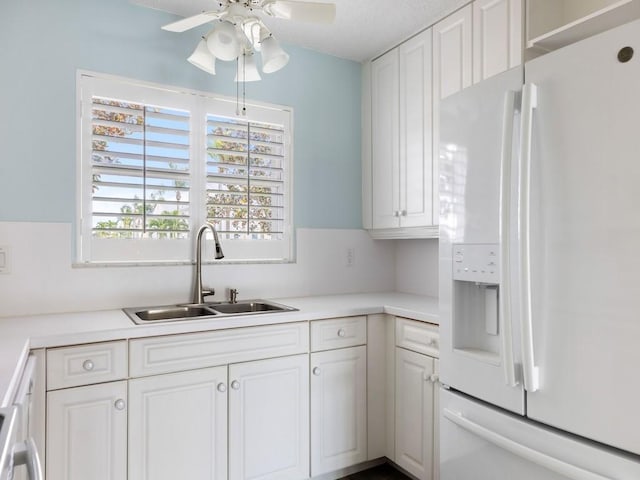 kitchen featuring ceiling fan, sink, white cabinets, range, and white fridge with ice dispenser