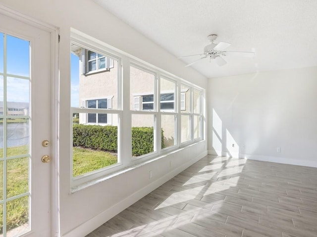 unfurnished sunroom featuring ceiling fan and a healthy amount of sunlight