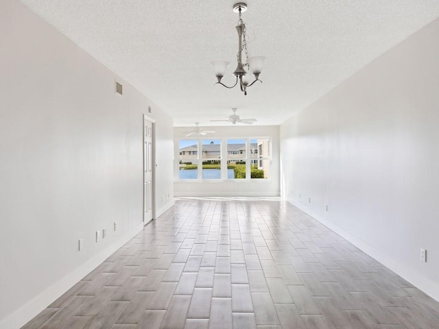 spare room featuring a chandelier, a textured ceiling, and light hardwood / wood-style floors