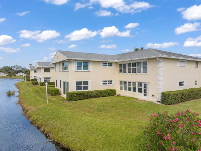 back of property with a water view and a yard