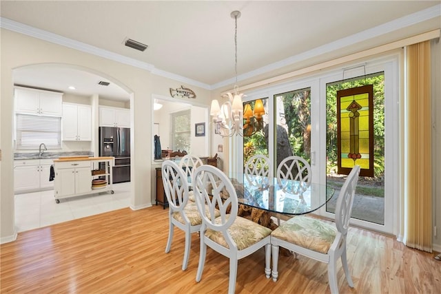 dining room featuring crown molding, sink, light hardwood / wood-style flooring, and an inviting chandelier