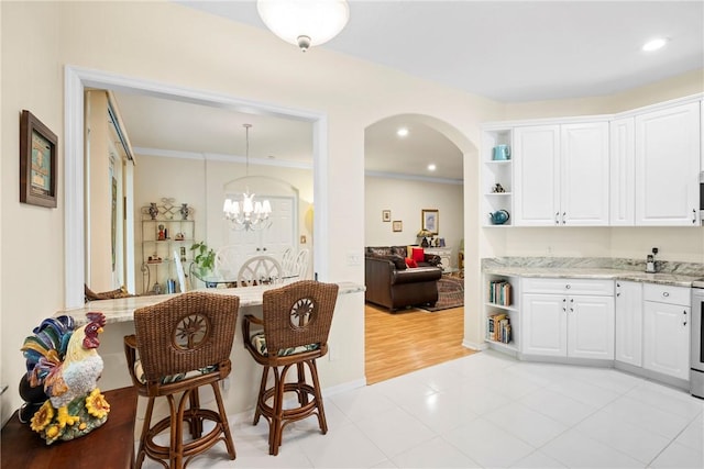 kitchen with white cabinets, light stone countertops, light tile patterned floors, decorative light fixtures, and a chandelier