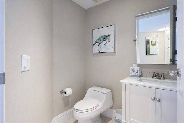 half bath featuring toilet, vanity, and baseboards
