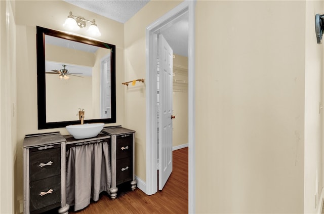 bathroom with vanity, hardwood / wood-style flooring, ceiling fan, and a textured ceiling