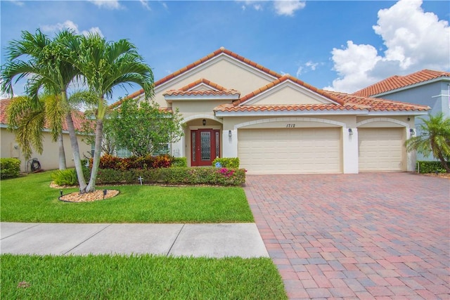 1712 Berkshire Cir SW, Vero Beach, FL 32968 - mediterranean / spanish-style home featuring a garage, decorative driveway, stucco siding, a front lawn, and a tile roof