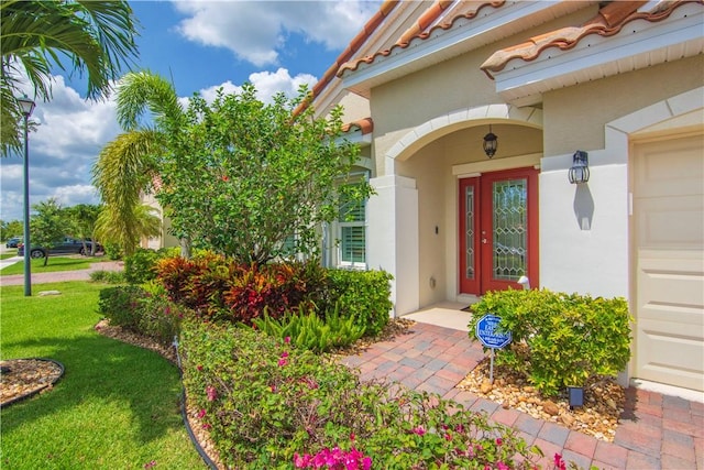 1712 Berkshire Cir SW, Vero Beach, FL 32968 - entrance to property with stucco siding, a lawn, and a garage