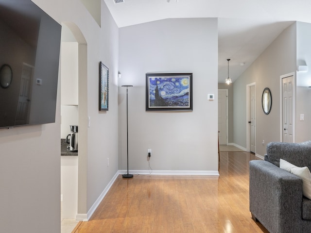 corridor with light hardwood / wood-style flooring and lofted ceiling