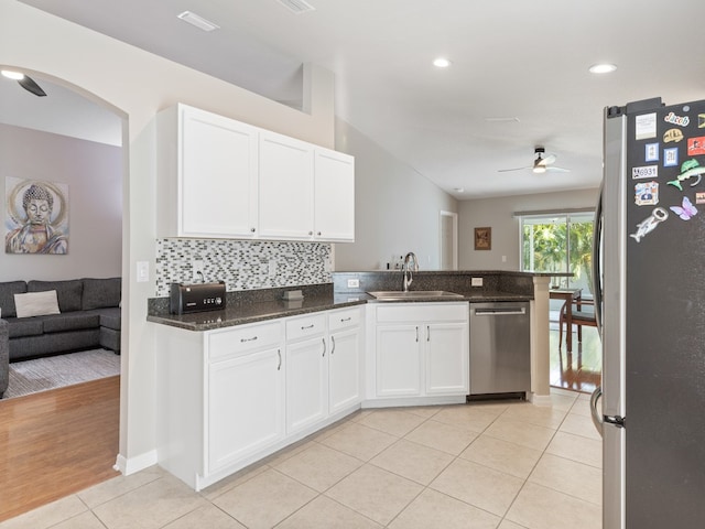 kitchen with white cabinetry, appliances with stainless steel finishes, sink, dark stone countertops, and light hardwood / wood-style flooring