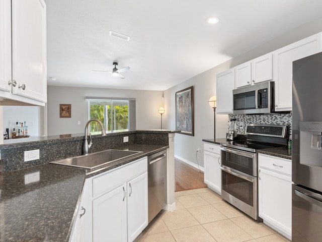 kitchen with dark stone counters, appliances with stainless steel finishes, sink, and white cabinets