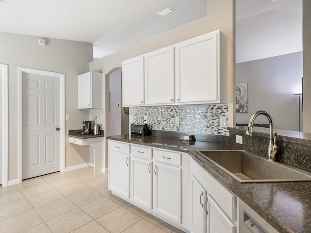 kitchen with vaulted ceiling, sink, light tile patterned floors, backsplash, and white cabinetry