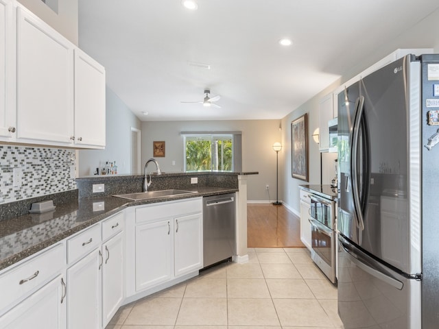 kitchen featuring white cabinets, sink, light tile patterned floors, appliances with stainless steel finishes, and dark stone countertops