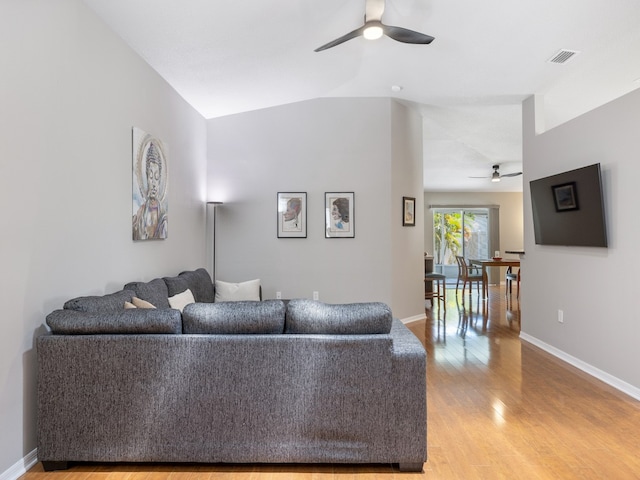 living room with hardwood / wood-style flooring, ceiling fan, and vaulted ceiling