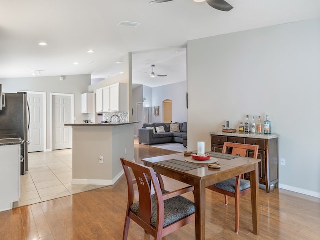 dining area with light hardwood / wood-style floors, ceiling fan, and vaulted ceiling