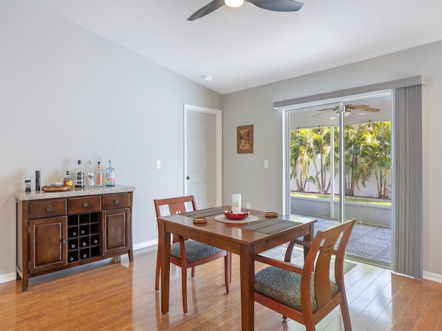 dining space with bar area, light hardwood / wood-style floors, lofted ceiling, and ceiling fan