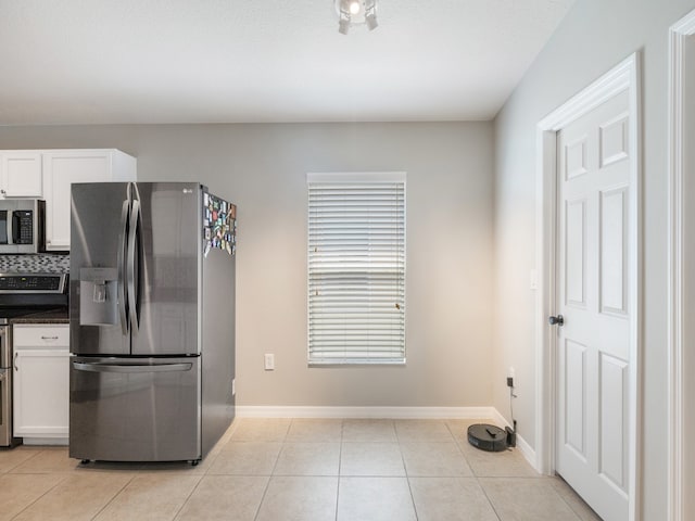 kitchen featuring white cabinetry, appliances with stainless steel finishes, light tile patterned flooring, and backsplash